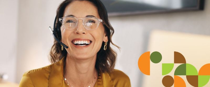 Asiakaspalveluhenkilö hymyilee ja katsoo kohtisuoraan lähikuvassa. 