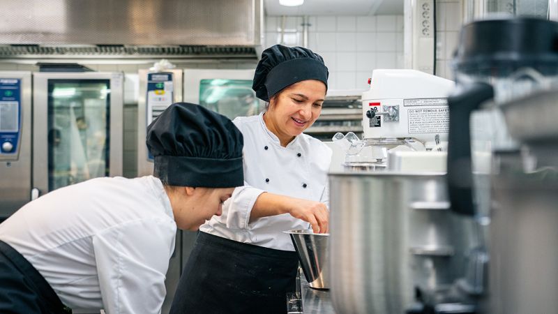 Kaksi Riverian ravintola- ja cateringalan opiskelijaa työskentelee opetuskeittiössä.