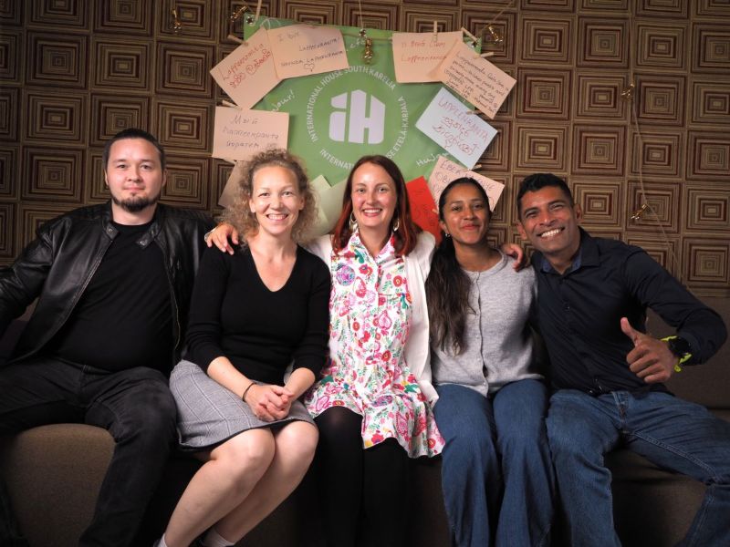 Viisi henkilöä istuu hymyillen rinnakkain International House South Karelian avajaisissa, kuvaaja Nilesh Tailor.