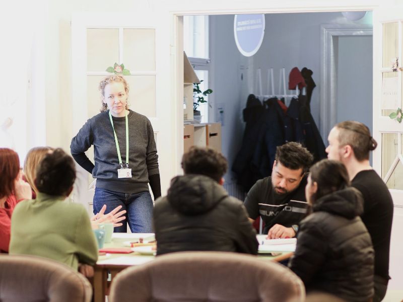 Ihmisiä kerääntyneenä saman pöydän ääreen.