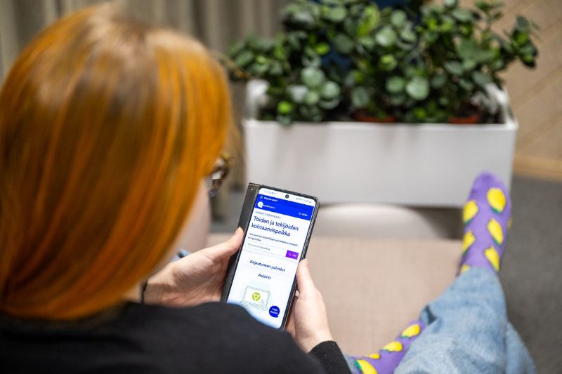 Henkilö istuu puhelin kädessään ja selaa Työmarkkinatoria.