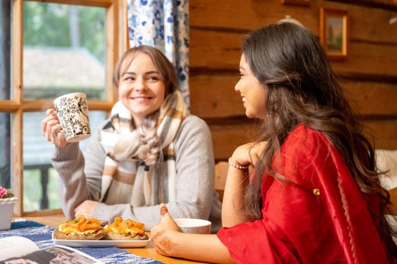 Kaksi henkilöä istuu pöydän ääressä ja juovat teetä<br/> 
