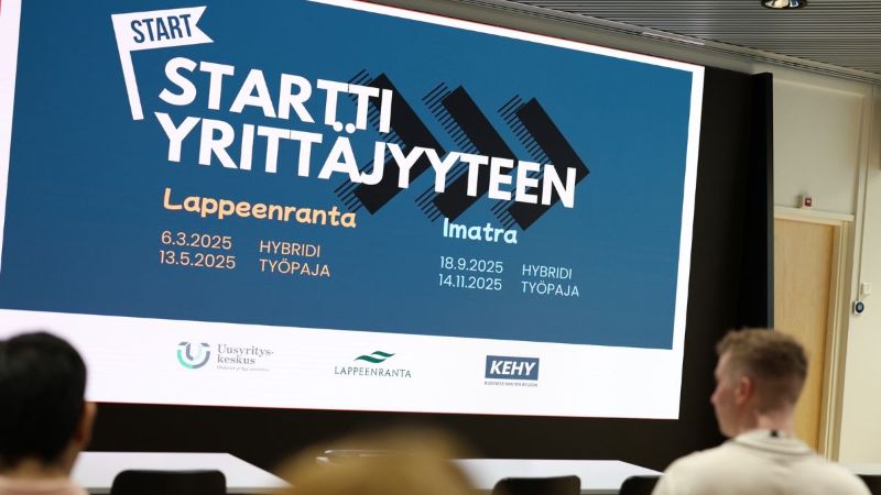 Ihmisiä katsomassa ruudulla näkyvää Startti Yrittäjyyteen -logoa. Ruudulla näkyy myös tapahtumien tarkemmat tiedot, jotka löytyvät myös tekstistä.