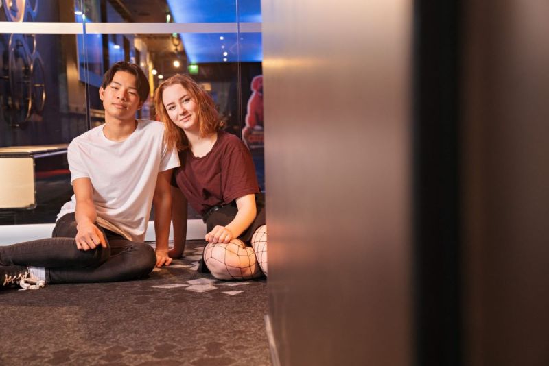 Kaksi henkilöä istuu lattialla.