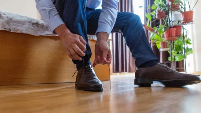 Mies sitoo kengännauhoja valmistautuakseen työhaastatteluun.