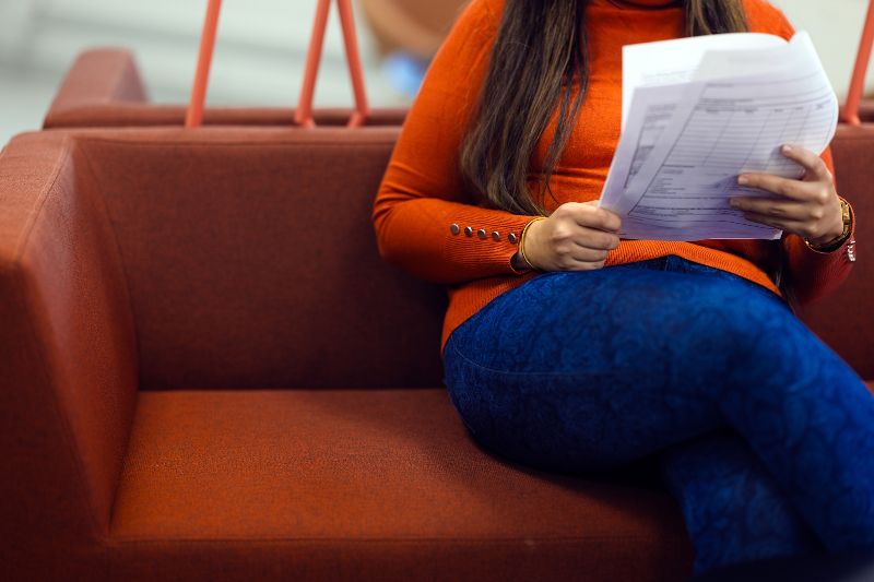 Nainen istuu ja pitää paperilomaketta kädessä.