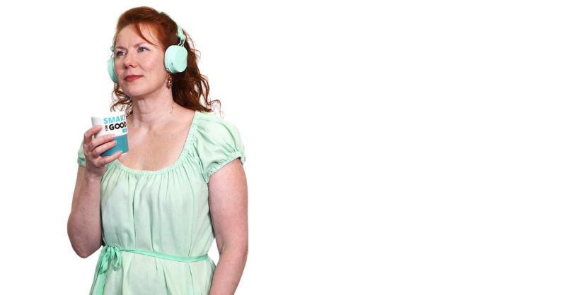 Kuvassa vihreään mekkoon pukeutunut nainen juo mukista ja kuuntelee kuulokkeet päässä.  