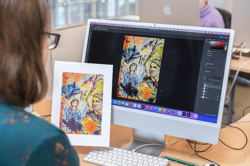 Henkilö istuu koneen ääressä ja katsoo printattua kuvaa.