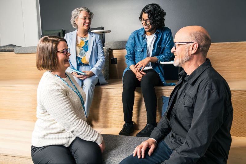 Kuvituskuva, jossa 4 ihmistä istuu portailla keskuselemassa.