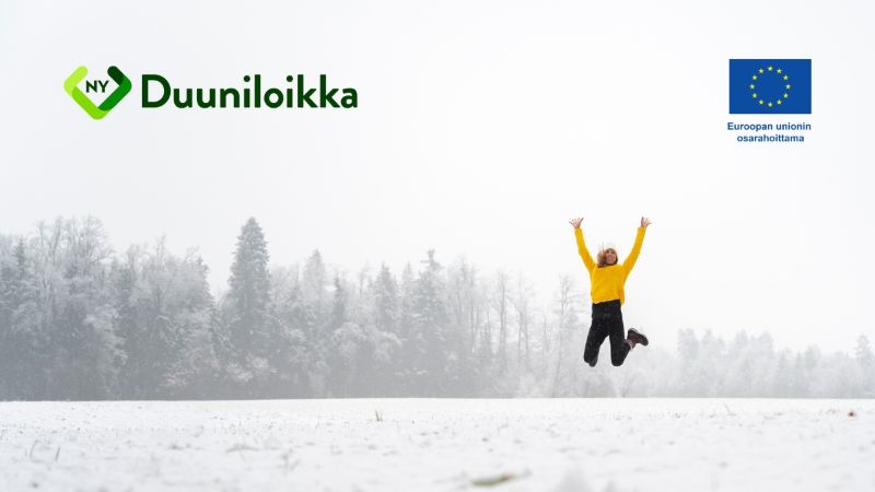 Oranssiin takkiin ja mustiin housuihin pukeutunut henkilö hyppää ilmaan. Taustalla luminen metsämaisema.