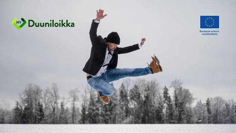 Mieshenkilö hyppää ilmaan taustallaan luminen talvimaisema.