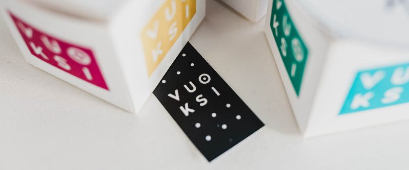 Värikkäitä paperikuutioita, joissa Vuoksin logo.