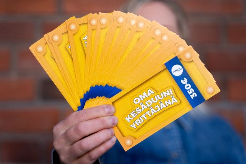 Käsi pitelee viuhkan muodossa olevia kesäyrittäjyysseteleitä.