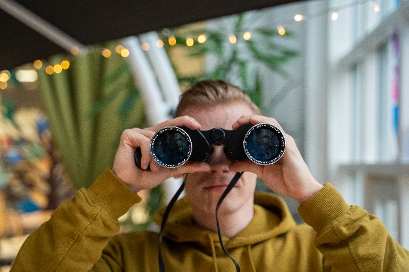 Kuvassa henkilö katsoo kiikareilla suoraan eteenpäin.